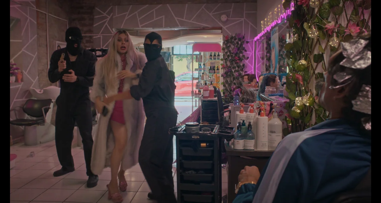 National Family (2023) movie still: medium — A modern hair salon with white tiled floors and neon pink accents. Two masked figures in black…