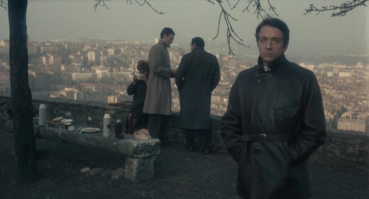 The Army of Shadows (1969) movie still: fullbody — A stone wall overlook provides a view of a sprawling city landscape during daytime. Four people…
