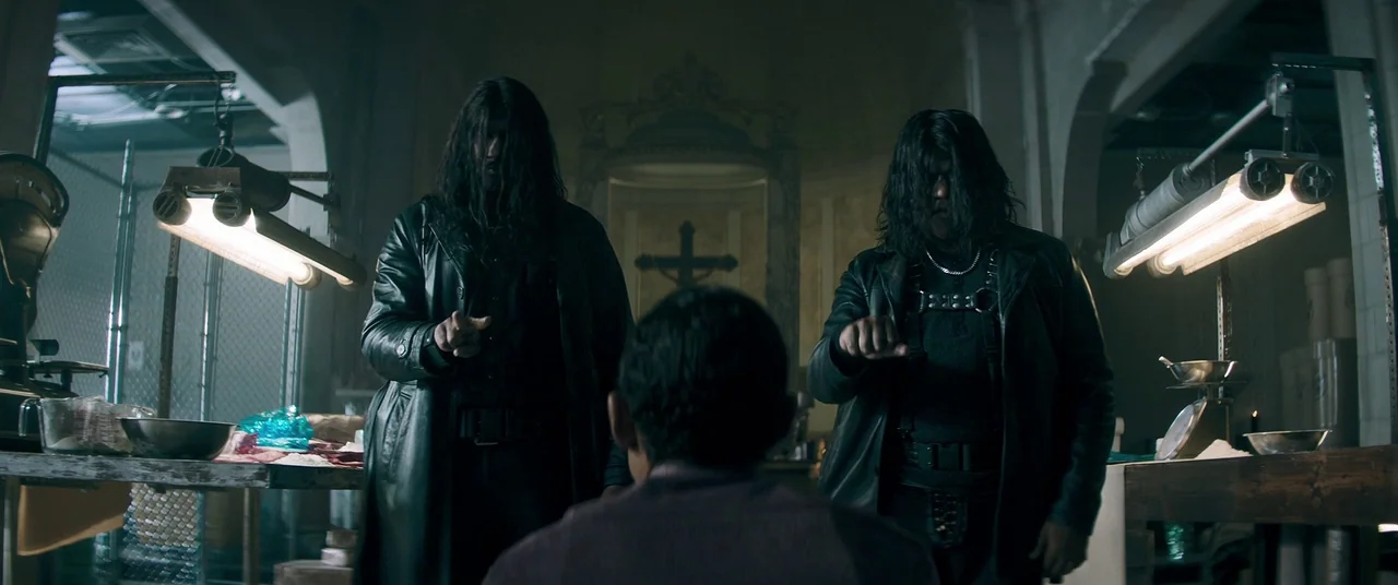 Keanu (2016) movie still: medium — A dark industrial space resembles a butcher shop with steel tables and hanging lights. Two long-haired men in…