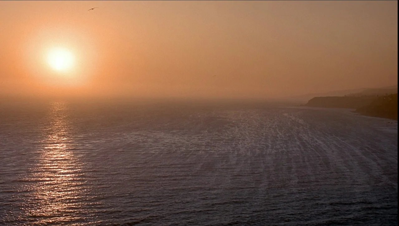Necronomicon: Book of Dead (1993) movie still: establishing — A wide view of the ocean during sunset with golden light reflecting on waves. A…