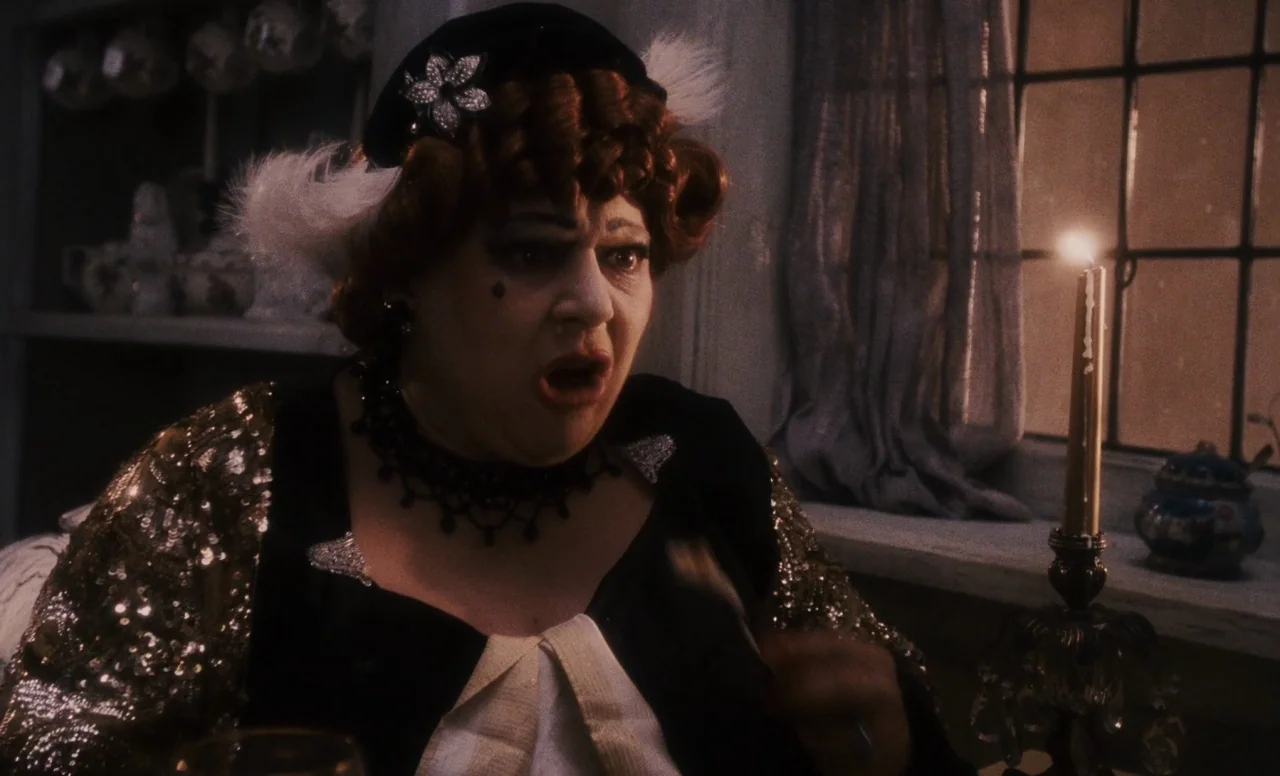 James and the Giant Peach (1996) movie still: medium — A woman sits in a dimly lit room with a paneled window behind her. She has a shocked facial…