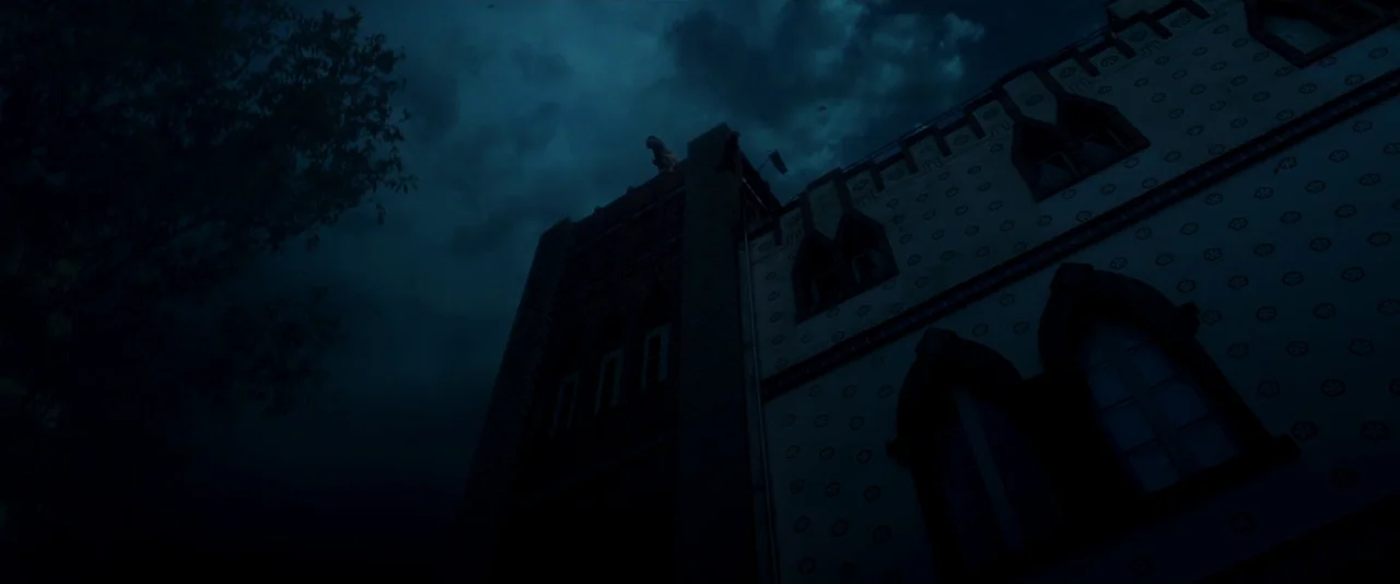 Crazy About Her (2021) movie still: establishing — An imposing gothic-style building exterior is captured against a dark, cloudy night sky. A lone…