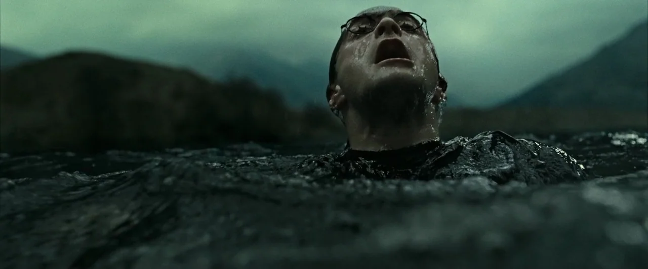 Harry Potter & The Deathly Hallows Part 2 (2011) movie still: closeup — A dark, choppy body of water is surrounded by distant, mist-covered…