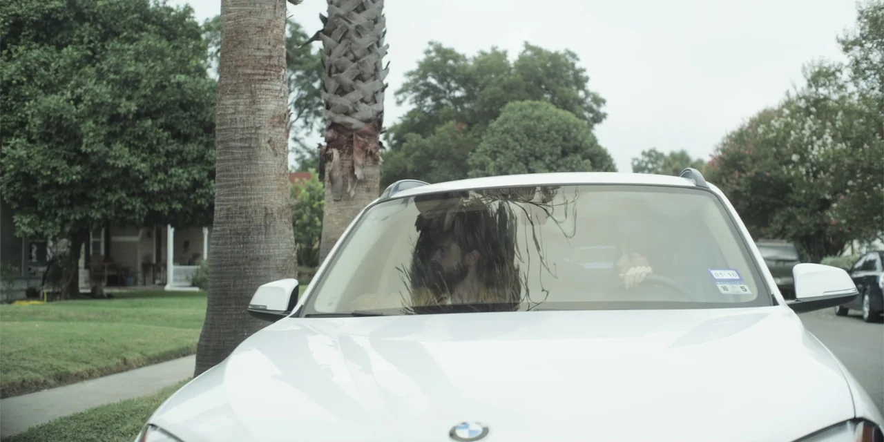 Stalked by My Doctor: A Sleepwalker's Nightmare (2019) movie still: medium — A white car is parked on a suburban street lined with palm trees. A man…