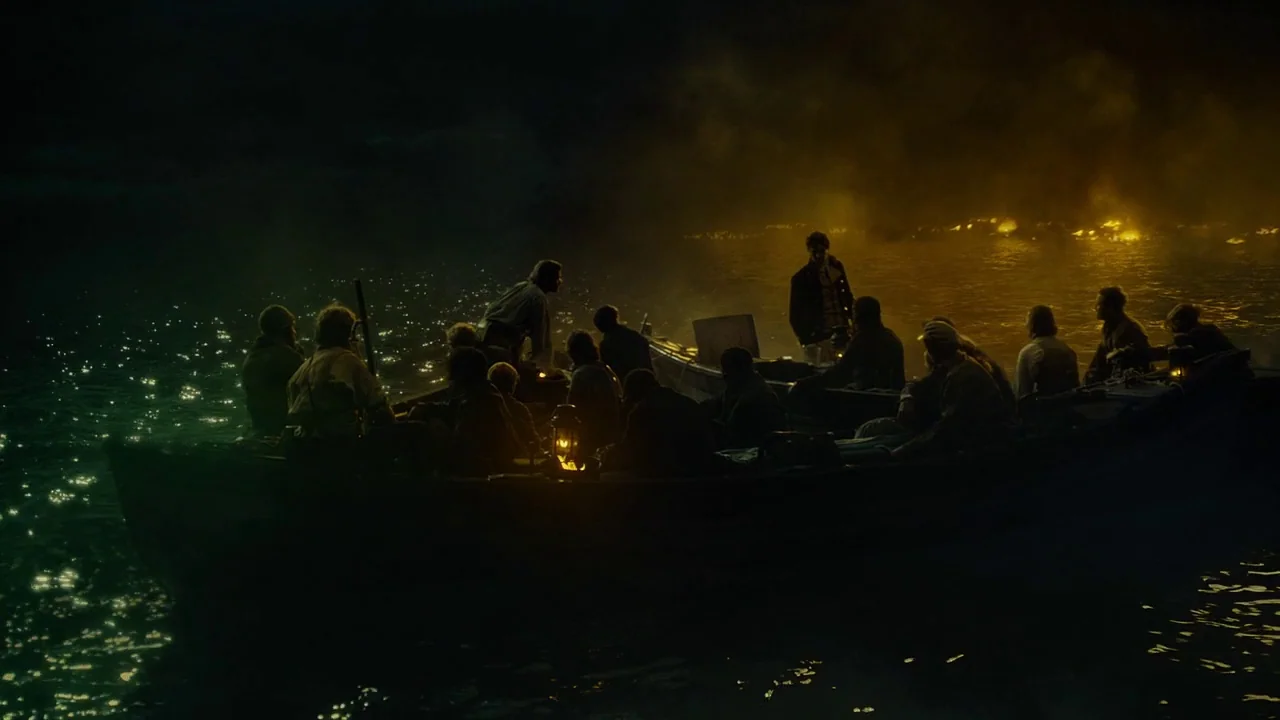 In The Heart of the Sea (2014) movie still: wide — Multiple men occupy two rowboats on a vast, dark body of water at night. A distant fire glows on…