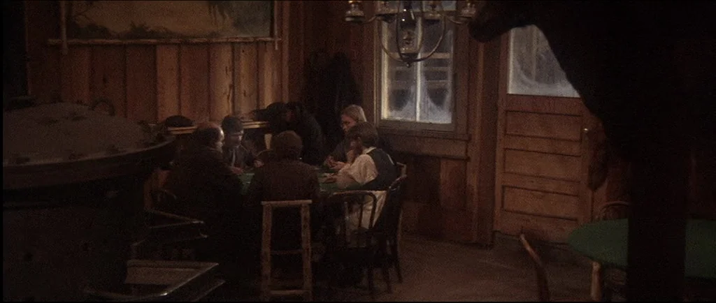 McCabe & Mrs.Miller (1971) movie still: wide — A dimly lit room features wood-paneled walls and a frosted window with frost patterns. Five men sit…