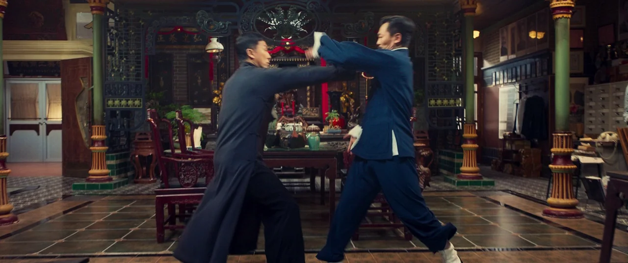 Ip Man 4: The Finale (2019) movie still: fullbody — A spacious room features ornate woodwork, tiled flooring, and multiple structural pillars. Two…