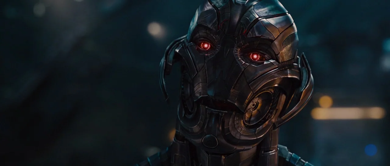 Avengers: Age of Ultron (2015) movie still: closeup — A dark laboratory interior with a mechanical subject positioned in the foreground. A robotic…