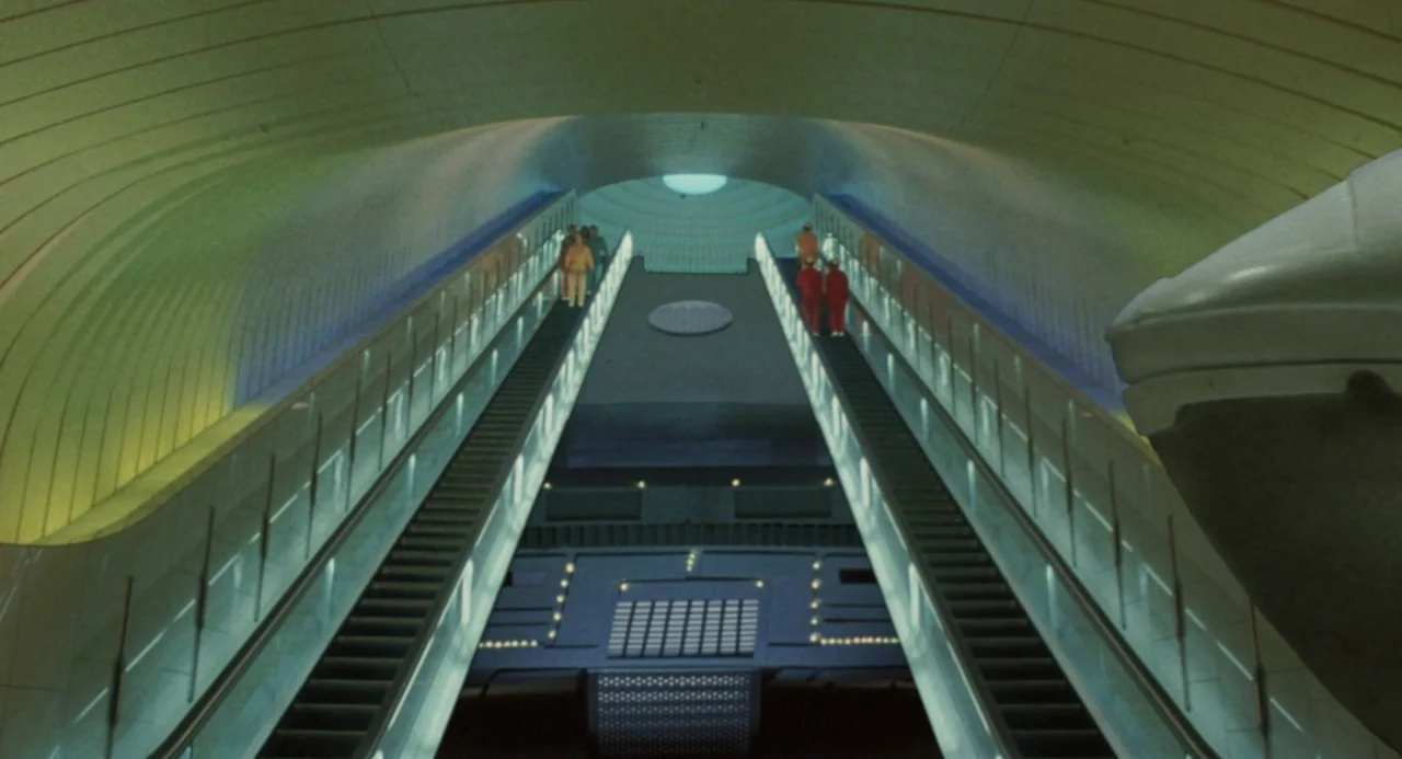 Godzilla vs. King Ghidorah (1991) movie still: wide — A modernist subterranean transit terminal features a curved vaulted ceiling and dual…