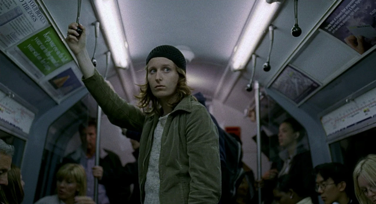 Swimming Pool (2003) movie still: medium — The interior of a crowded public transit car is filled with commuters at night. A woman stands in the…