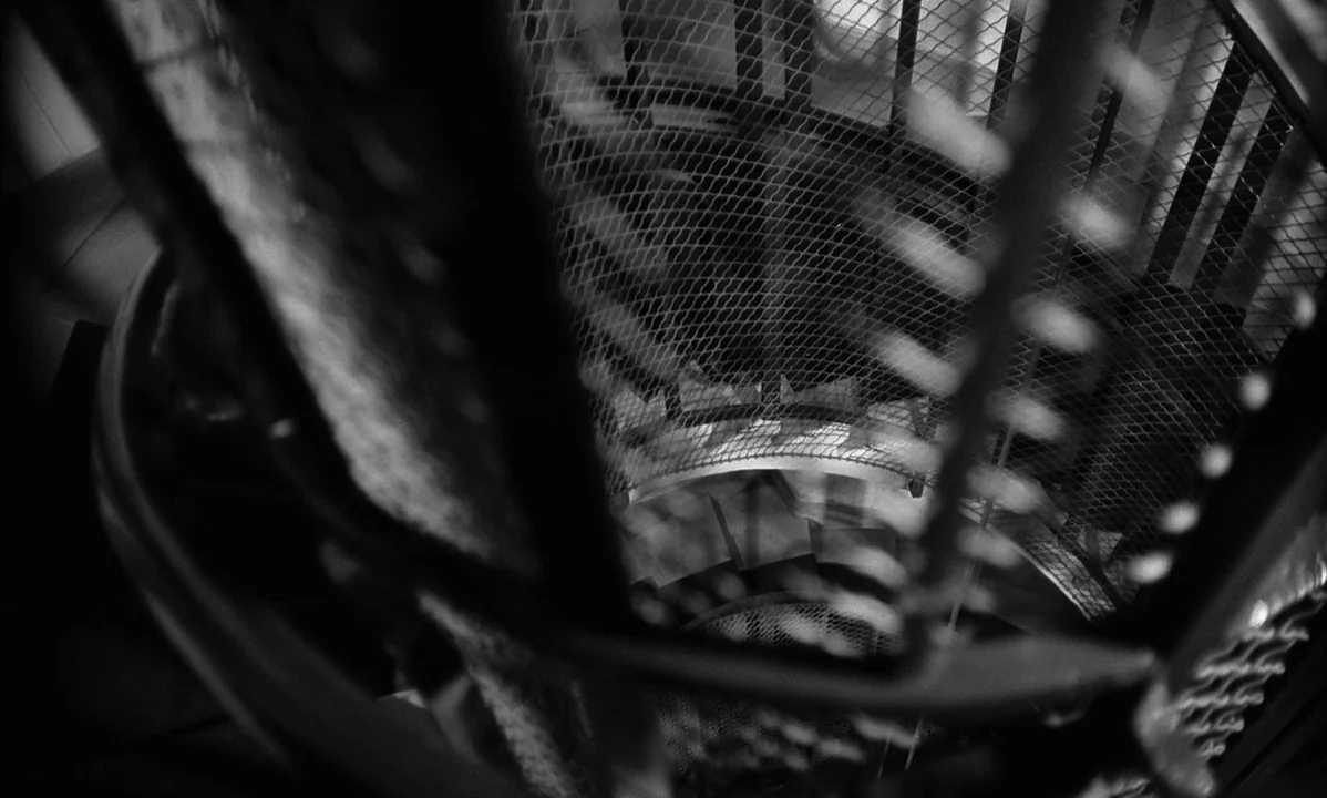 La Peau Douce (The Soft Skin) (1964) movie still: establishing — A metal spiral stairwell with a safety mesh enclosure descends into a dark abyss.…
