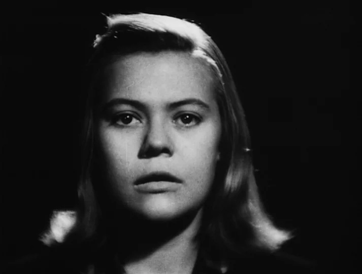 Port of Call (1948) movie still: closeup — The subject is positioned against a completely black background. A young woman looks directly toward the…
