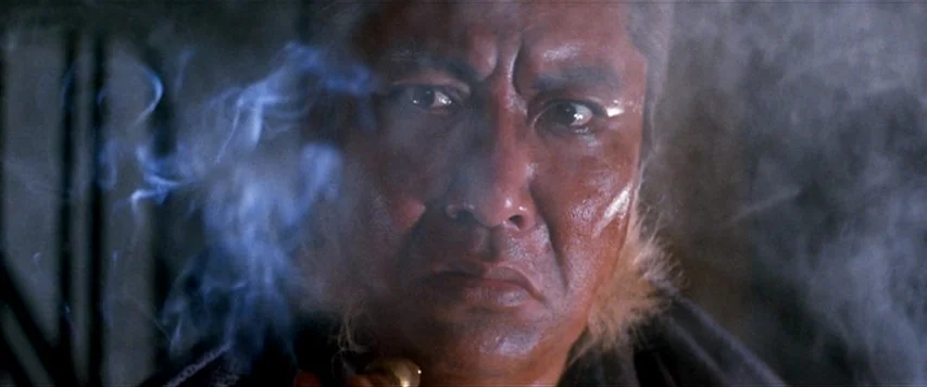 Lone Wolf and Cub: Sword of Vengeance (1972) movie still: closeup — A dark indoor setting is filled with thin, swirling blue smoke. An elderly man…