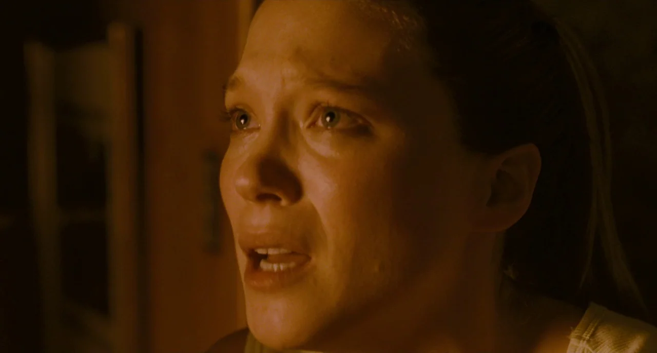 It’s Only The End Of The World (2016) movie still: closeup — A dimly lit room with dark, obscured surroundings and warm color tones. A woman with a…