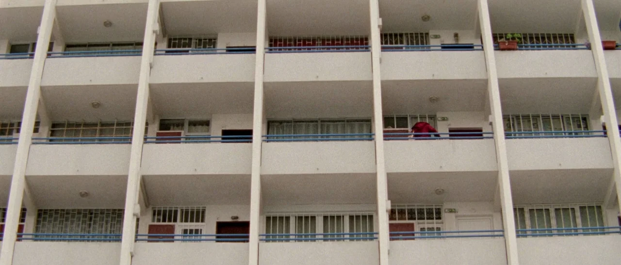 Arabian Nights: Volume 2 The Desolate One (2015) movie still: wide — A multi-story concrete apartment block features repeating balconies with blue…