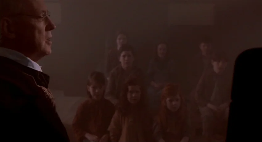 The Secret Of Roan Inish (1994) movie still: medium — A dark, sparsely furnished room filled with a thick, warm-toned haze. An elderly man in a…