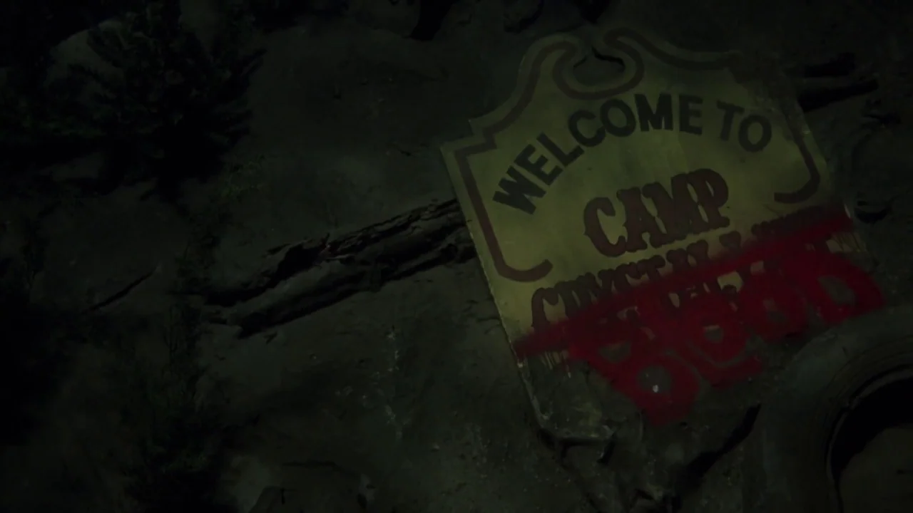 Friday the 13th Part VI: Jason Lives (1986) movie still: closeup — A dirty, weathered wooden sign lies on a dark, rocky ground at night. The sign…