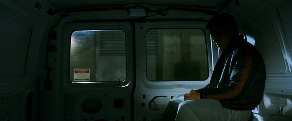 Ocean’s Eleven (2001) movie still: medium — The interior of an empty cargo van features white metal walls and rear doors. A man sits alone in the…