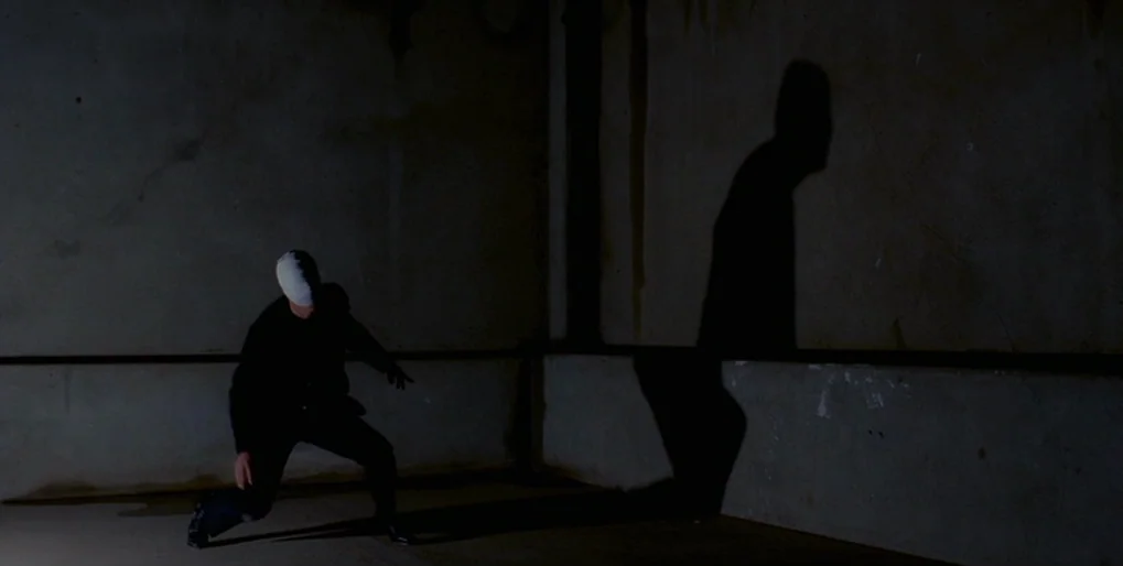 Dominion: Prequel to the Exorcist (2005) movie still: wide — An empty corner of a concrete room has stained walls and dark shadows. A bandaged…