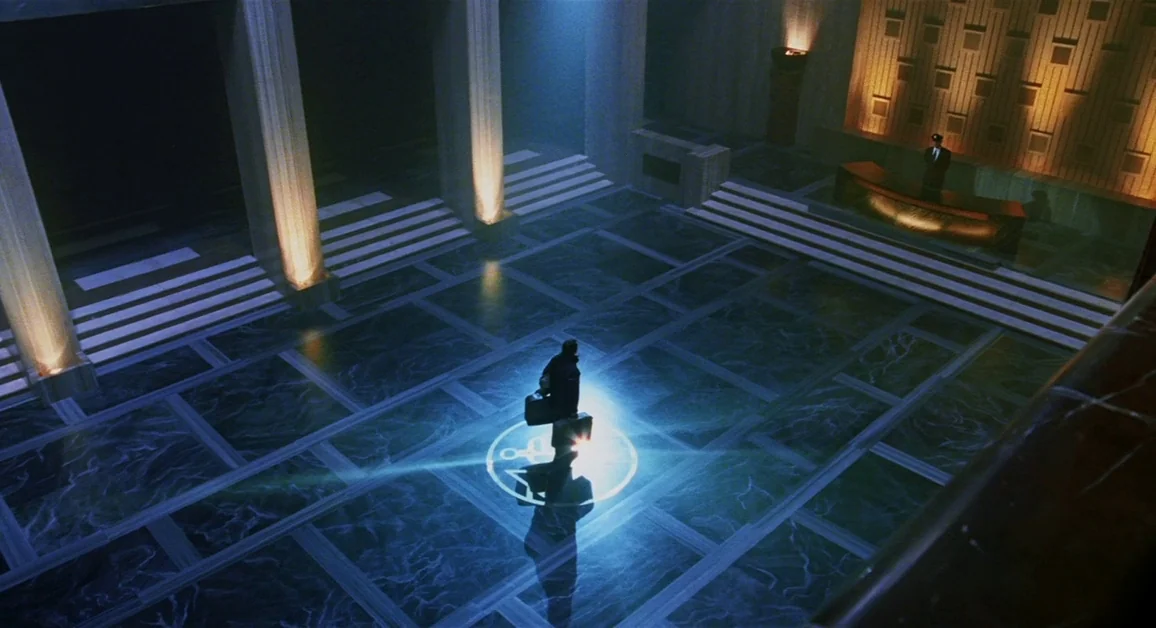 Hellboy (2004) movie still: wide — A dark marble lobby with tall pillars and a reception desk features a glowing symbol. A man stands alone in the…