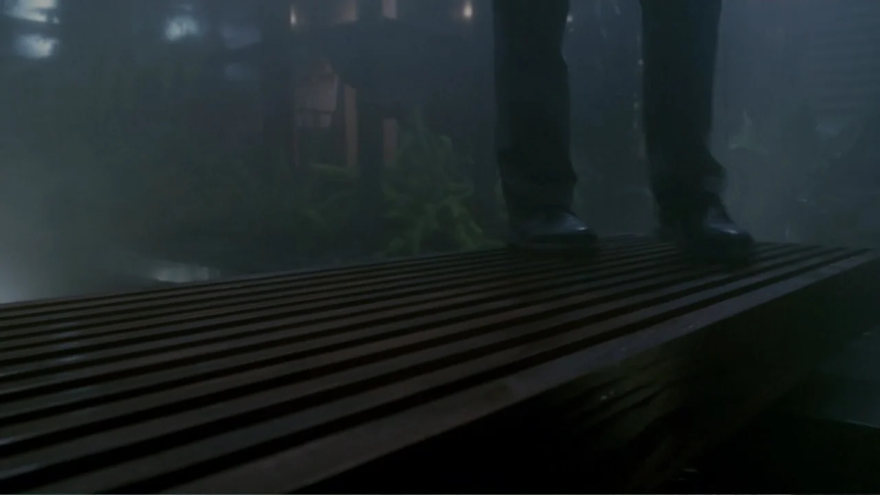 When a Stranger Calls (2006) movie still: closeup — A dark outdoor space features thick fog obscuring a slatted wooden surface. The lower legs and…