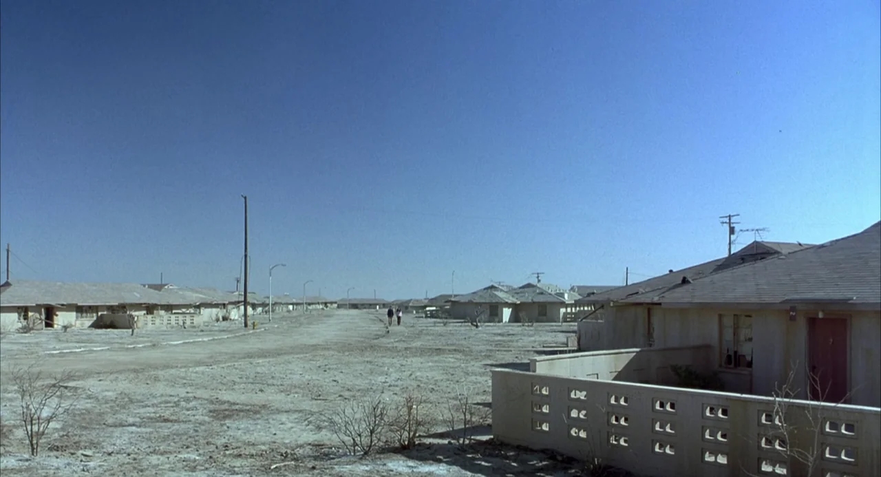 Hulk (2003) movie still: establishing — A desolate residential neighborhood features rows of single-story, boxy houses made of light-colored stucco.…