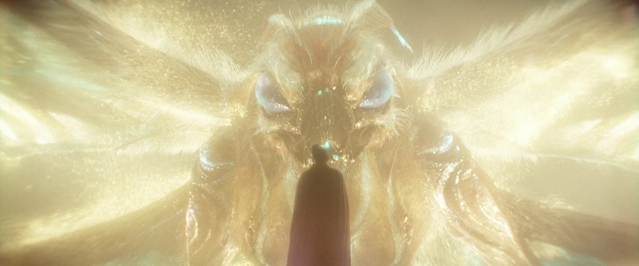 Godzilla x Kong: The New Empire (2024) movie still: wide — A colossal golden moth creature with glowing wings hovers in a luminous, hazy atmosphere.…