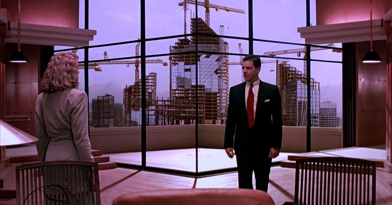 Darkman (1990) movie still: fullbody — A modern, minimalist office suite overlooks a city skyline under construction at twilight. A man in a dark…