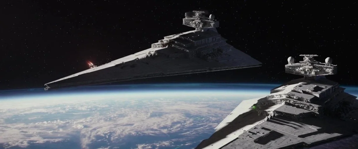 Rogue One: A Star Wars Story (2016) movie still: wide — Two massive gray triangular starships float above a planet with dense white cloud cover. The…