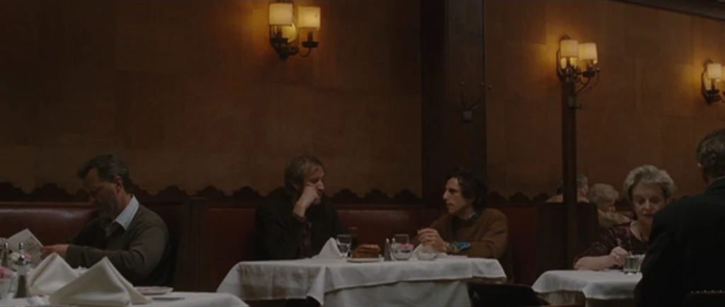 Greenberg (2010) movie still: wide — A dimly lit restaurant interior features dark wood paneling and red leather booths. Several patrons sit at…