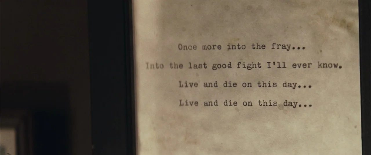 The Grey (2012) movie still: closeup — A piece of aged, stained paper with typewritten text sits inside a dark frame. The text reads poetry lines…