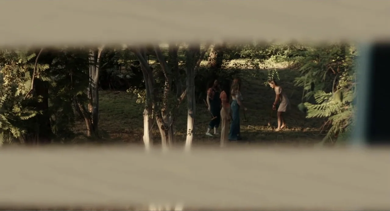 Ted Bundy: American Boogeyman (2021) movie still: wide — A group of four women plays a game of croquet on a grassy lawn. Trees surround the area as…