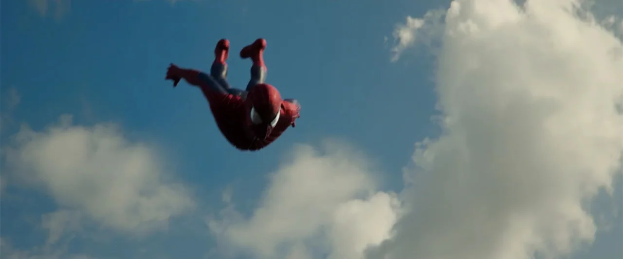 The Amazing Spider-Man 2 (2014) movie still: wide — An expanse of blue sky filled with scattered white clouds occupies the view. A masked figure in…