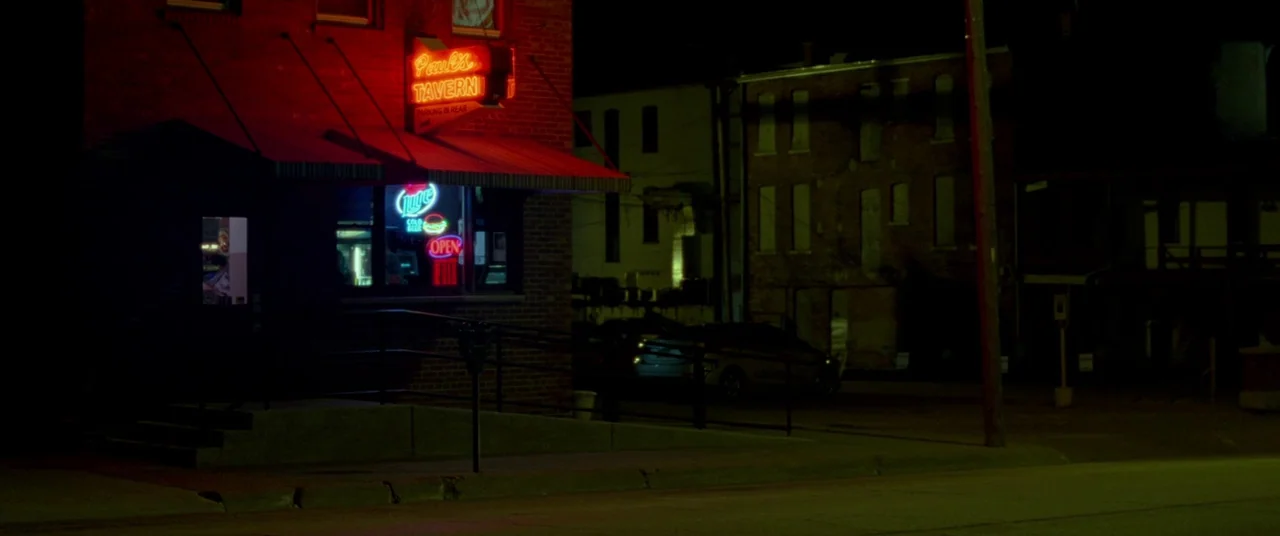 Mississippi Grind (2015) movie still: wide — A brick building at night features a prominent red neon sign reading Paul's Tavern. Several smaller…