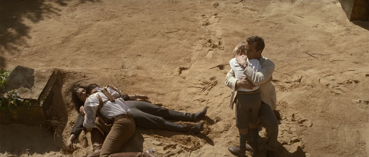 The Mummy Returns (2001) movie still: wide — An expanse of sunlit sand features a small group of people in 1940s attire. One man stands embracing a…