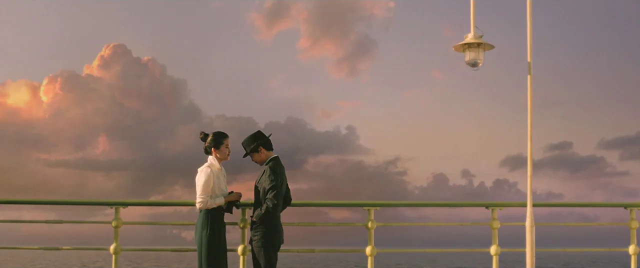 The Handmaiden (2016) movie still: fullbody — A ship railing overlooks an ocean horizon during a colorful sunset with heavy clouds. A woman in a…