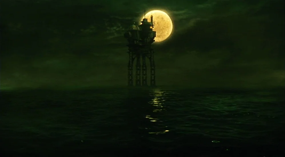 The City Of Lost Children movie still: establishing — A tall, industrial metal tower stands on stilts in the middle of dark water. The full moon…