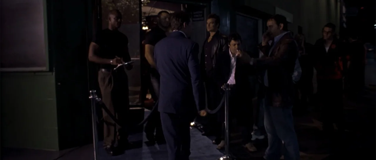 Shade (2003) movie still: fullbody — The exterior of a nightclub at night features a velvet rope barrier. A group of men stands near the entrance…