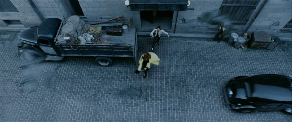 The Curious Case Of Benjamin Button (2008) movie still: wide — A stone-paved street features a loading truck parked against a building facade. A…