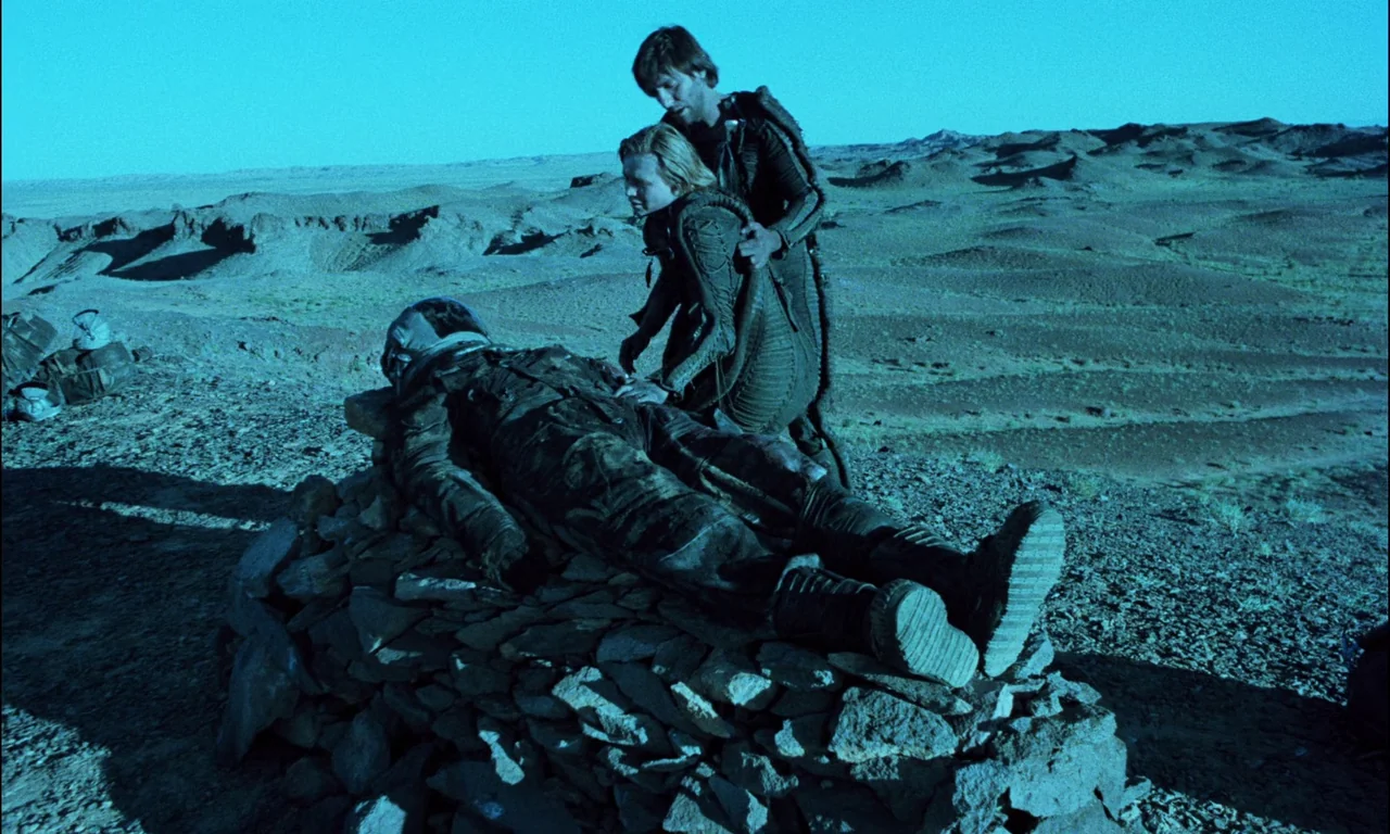 On The Silver Globe (1988) movie still: fullbody — A barren, rocky desert expanse extends to the horizon under a twilight sky. Two people stand over…