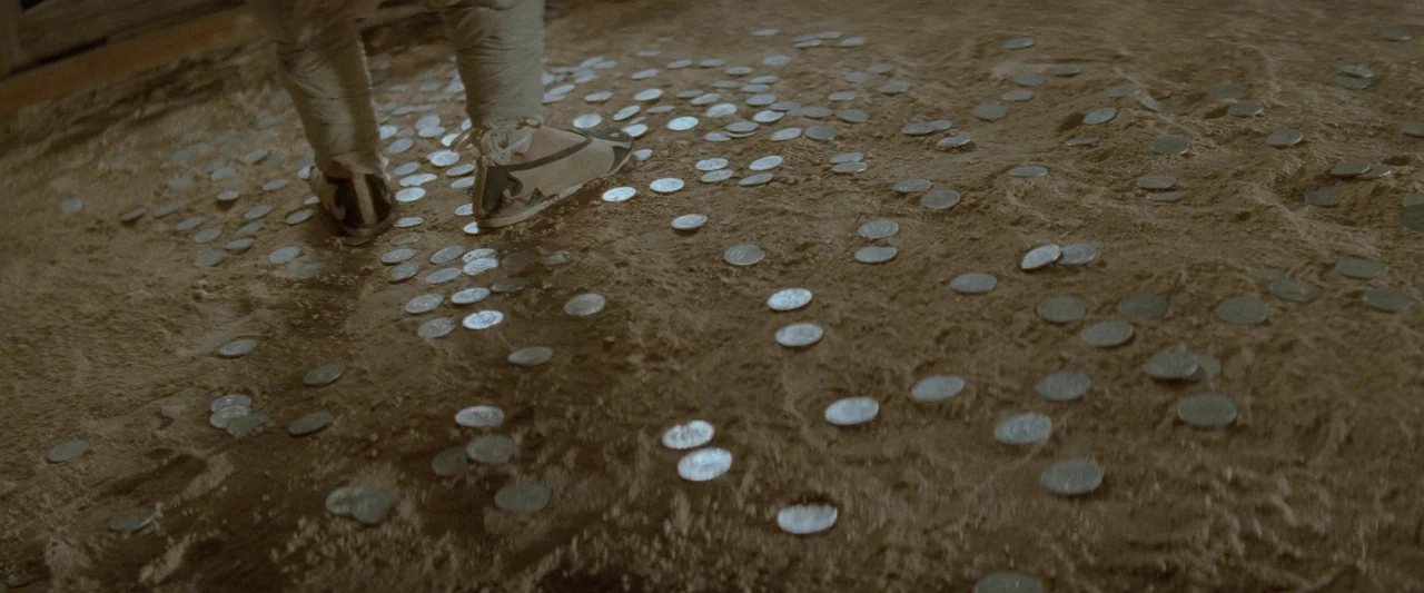 Once Upon a Time in China (1991) movie still: medium — A patch of dry dirt is covered in scattered, small metallic silver coins. A person stands…