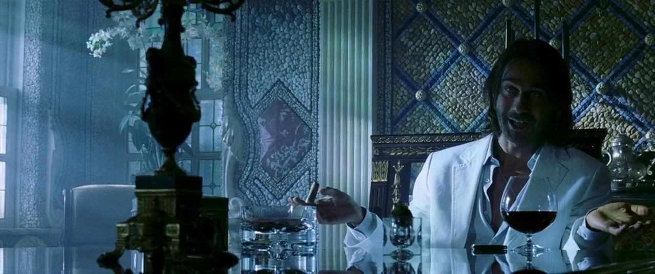 Bad Boys II (2003) movie still: medium — A dimly lit room features walls covered in intricate pebble mosaics and ornate furniture. A man in a white…