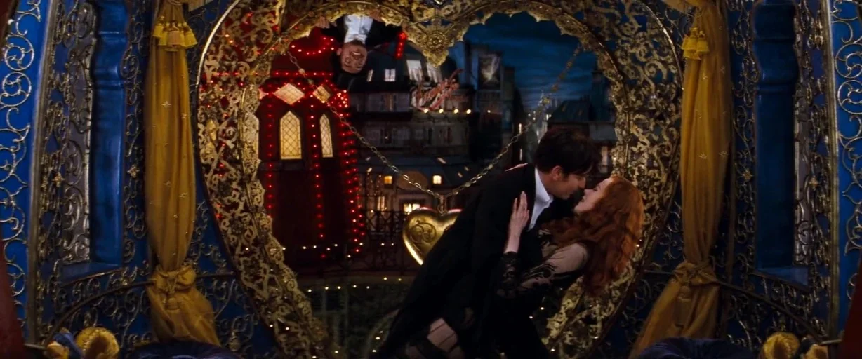 Moulin Rouge! (2001) movie still: medium — A theatrical structure decorated with ornate gold metalwork in a heart shape framing. A man in a suit and…
