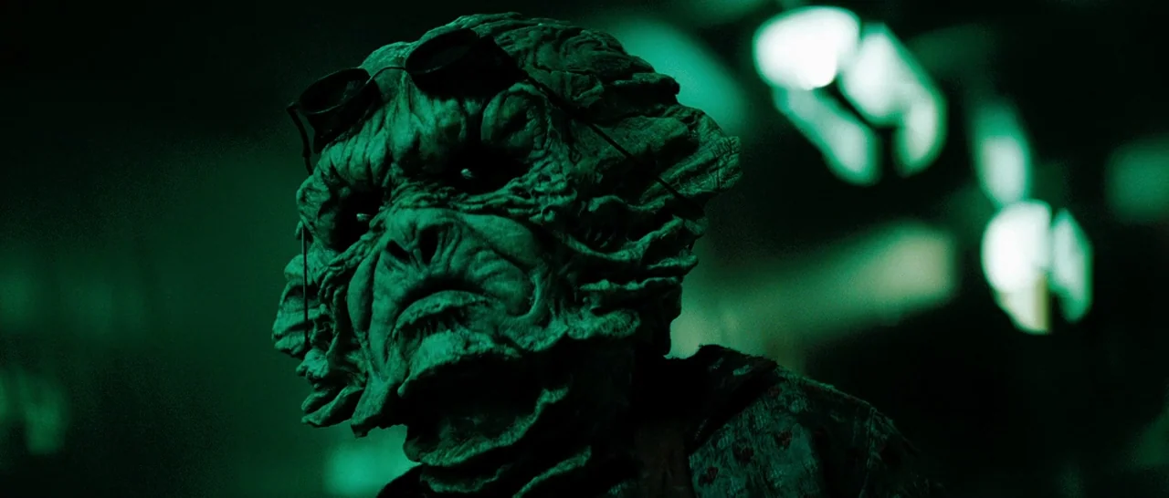 Star Trek (2009) movie still: closeup — A dark environment is filled with sharp, out-of-focus green light sources. An amphibian creature with…