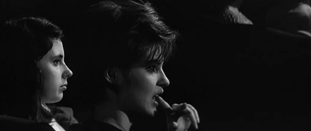 Antoine and Colette (1962) movie still: medium — Two women sit side by side in a darkened auditorium while watching a movie. They are illuminated by…