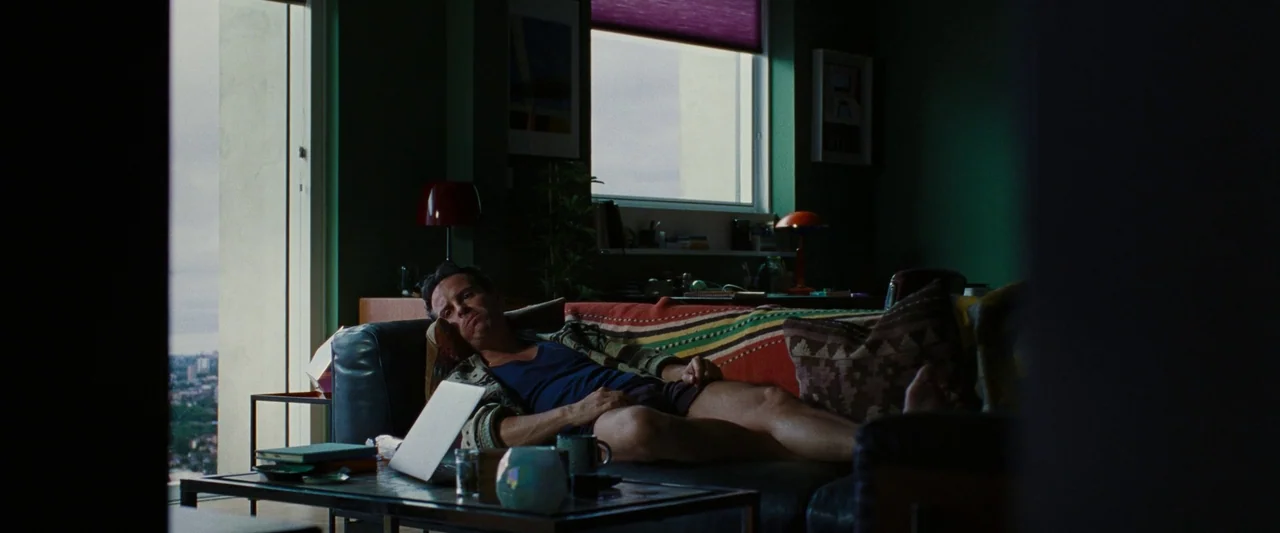 All Of Us Strangers (2023) movie still: medium — A dark living room with deep green walls features a large leather sofa.