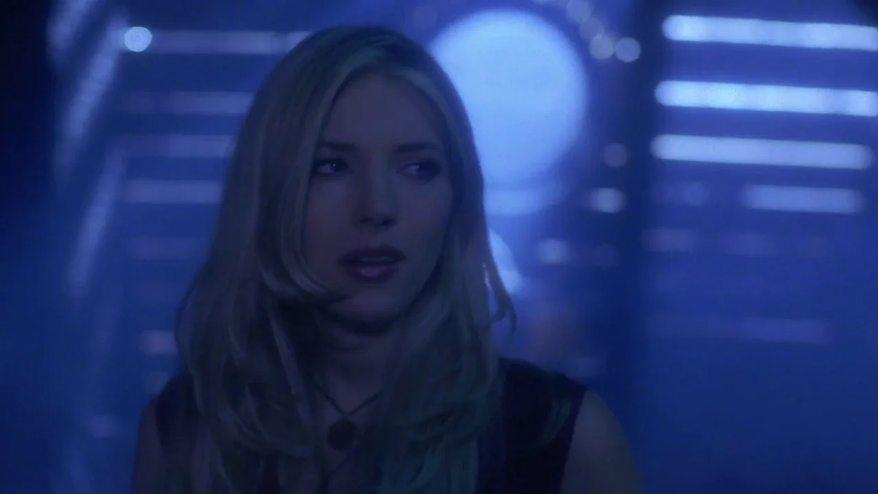 Hellraiser: Hellworld (2005) movie still: closeup — A dimly lit club interior features blurred blue light patterns on the walls. A blonde woman…