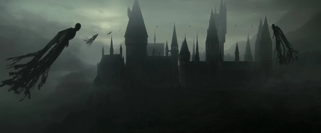 Harry Potter & The Deathly Hallows Part 2 (2011) movie still: establishing — A gothic castle looms over a dark, rocky cliffside under an overcast,…