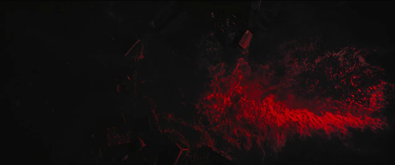 The Batman (2022) movie still: establishing — A dark, wet urban street surface is saturated in intense, vibrating red light. Puddles and reflective…