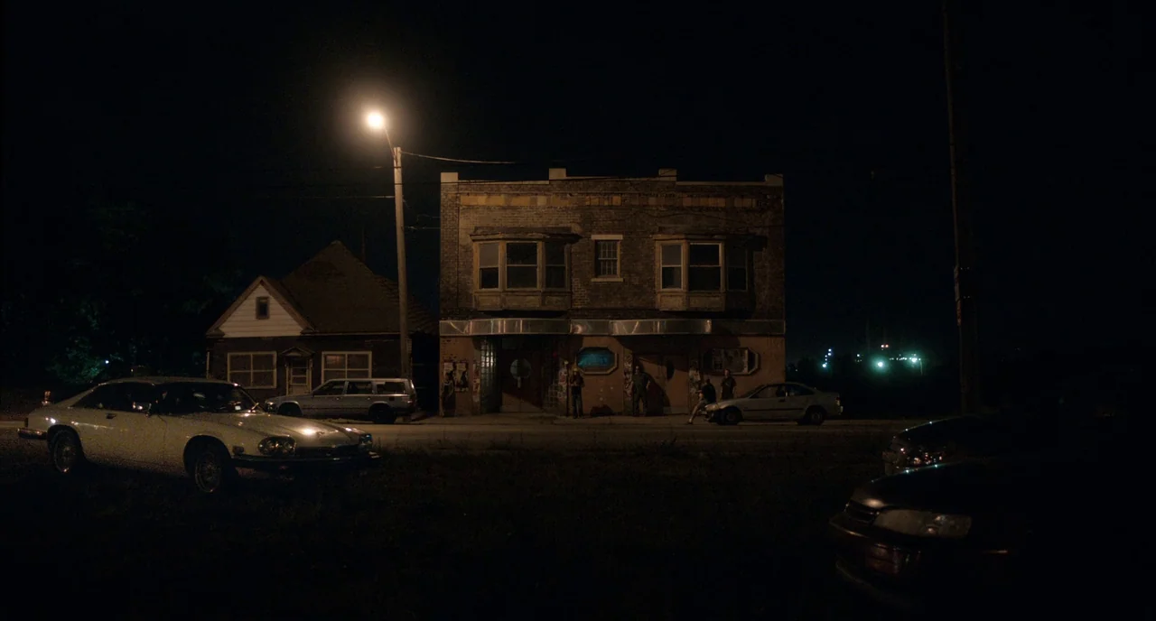 Only Lovers Left Alive (2013) movie still: wide — A two-story brick building stands at night with several cars parked on the roadside. A tall…